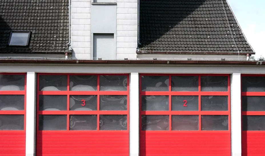 Fahrzeughalle einer Feuerwache mit roten Toren und Steildach